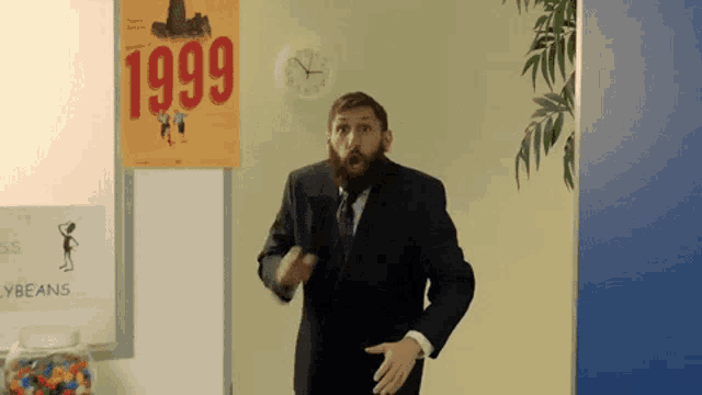 a man in a suit and tie standing in front of a sign that says 1999
