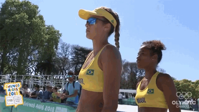 two female volleyball players from brasil are standing on a beach
