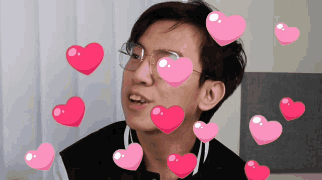 a man with glasses and pink hearts surrounding his face