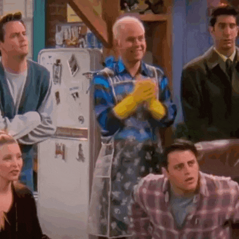 a group of people are sitting around a table in front of a refrigerator wearing aprons and gloves .