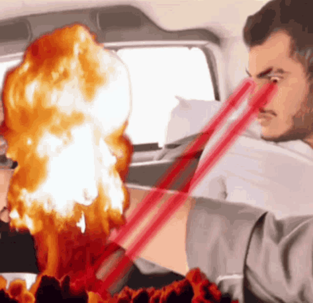 a man is holding a red straw in front of an explosion in a car