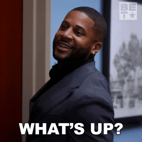 a man in a suit is smiling and asking what 's up