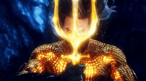 a man in a gold suit is holding a trident in his hand .