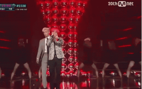 two men with red hair are dancing on a stage in front of a red wall .