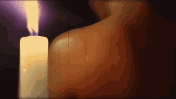 a person 's back is shown with a lit candle in the background
