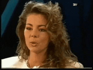 a woman with long curly hair is talking on a tv screen .