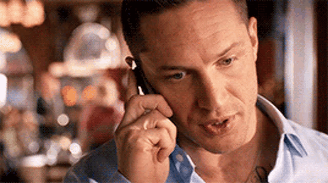 a man with a tattoo on his chest is talking on a cell phone .