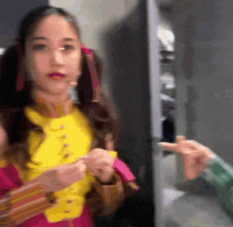 a woman in a yellow jacket is standing next to a refrigerator