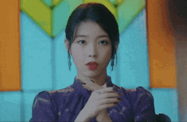 a woman in a purple dress is holding her hands out in front of a colorful background .