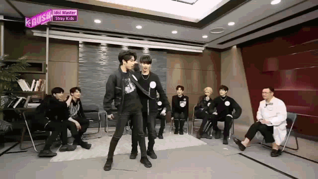 a group of young men are dancing in front of a sign that says idol master stray kids
