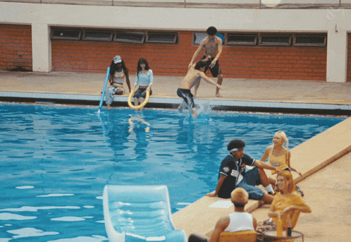 a group of people are gathered around a swimming pool including a man wearing a jersey that says ' a '
