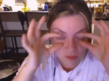 a woman is covering her eyes with her hands and making a face .