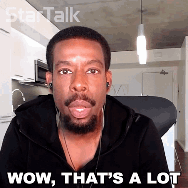 a man wearing headphones says wow that 's a lot in front of a kitchen
