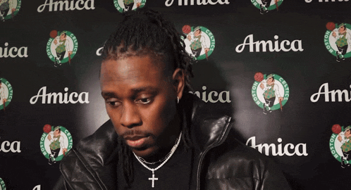 a man is standing in front of a wall with boston celtics logos