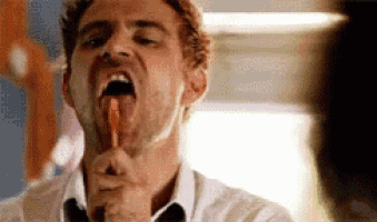a man is holding a lollipop in his mouth and licking it .