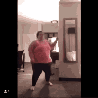 a woman is dancing in a room with a mirror .