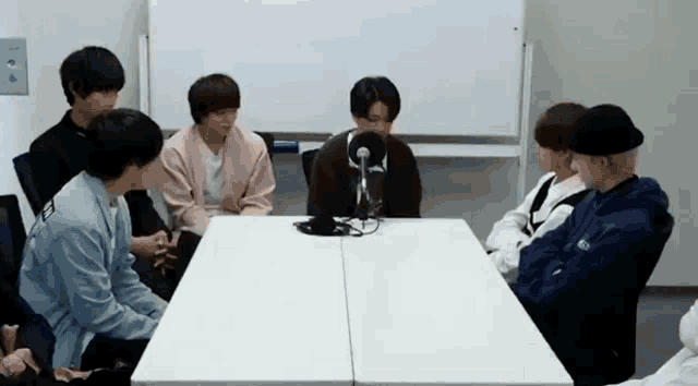 a group of people are sitting around a table with a microphone on it