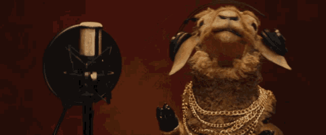 a sheep wearing headphones and a gold chain singing into a microphone