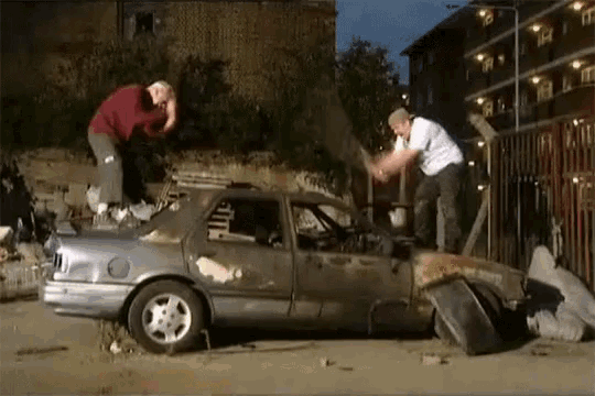 a man is standing on top of a broken car