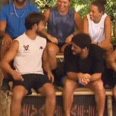 a group of people are sitting on a bench with one man wearing a white shirt with the letter w on it .