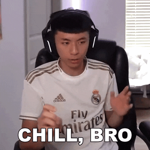 a man wearing headphones and a fly emirates jersey is sitting in a chair .