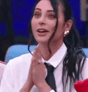 a woman in a white shirt and black tie is praying with her hands folded .