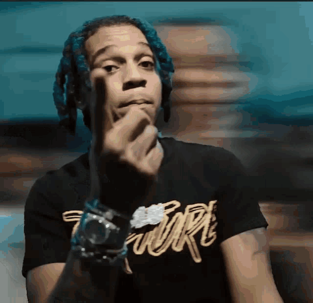 a man with blue hair is wearing a black t-shirt that says torx