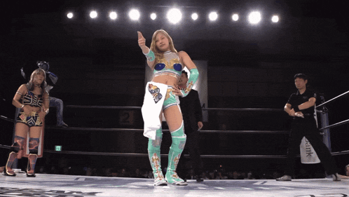 a woman in a wrestling ring giving a thumbs up with the number 2 behind her