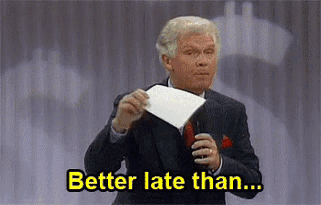 a man in a suit and tie is holding a piece of paper and says `` better late than ... '' .