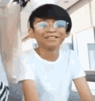 a young boy wearing glasses and a white t-shirt is making a funny face .