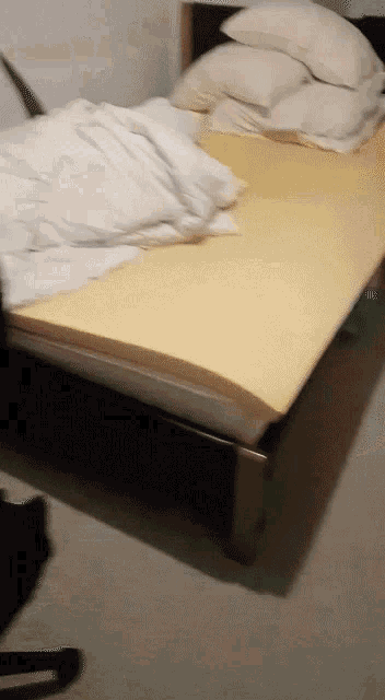 a bed with a yellow comforter and white sheets and pillows