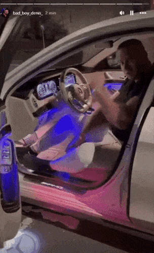 a man is sitting in the driver 's seat of a car with the door open .