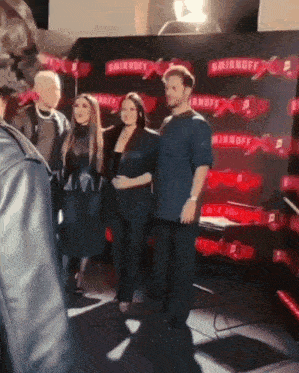 a group of people standing in front of a sign that says smirnoff x