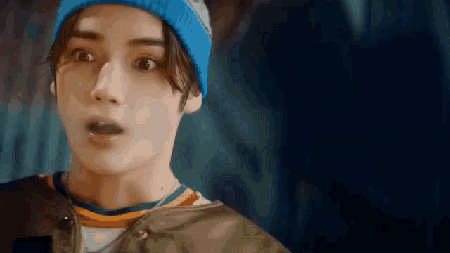 a close up of a person wearing a blue beanie and a green jacket .