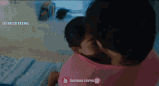a woman in a pink shirt is holding a baby in her lap