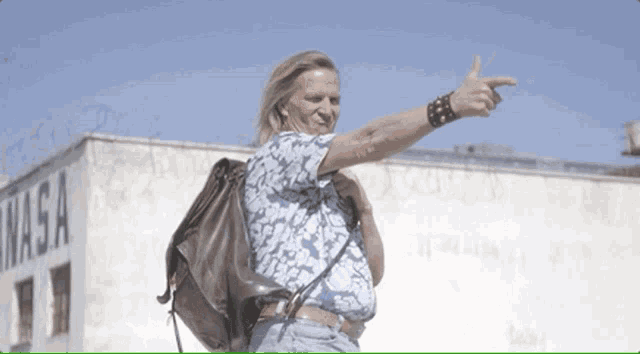 a man with a backpack is pointing to a nasa sign