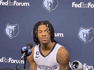 a basketball player is sitting in front of a microphone in front of a fedex forum wall .