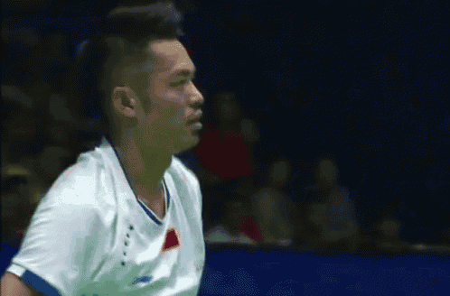 a man in a white shirt with a blue stripe on the sleeve is playing badminton