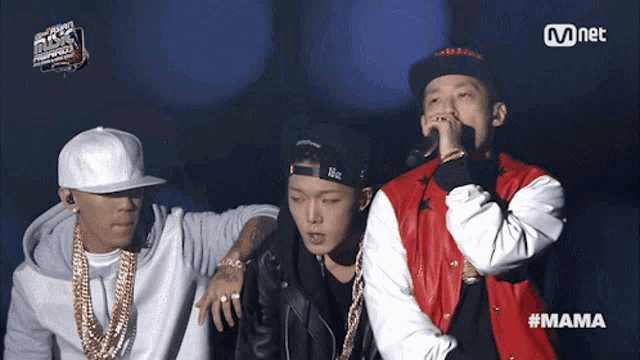 three men are standing next to each other and one of them is wearing a red jacket