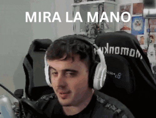 a man wearing headphones is sitting in front of a microphone with the words mira la mano written above him