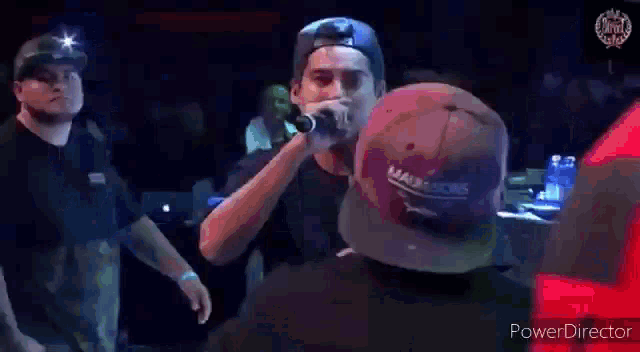 a man is singing into a microphone while standing in a crowd .