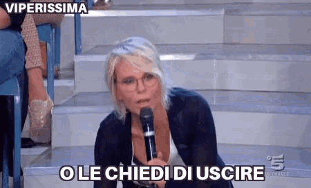 a woman is kneeling down holding a microphone and says ole chiedi di uscire