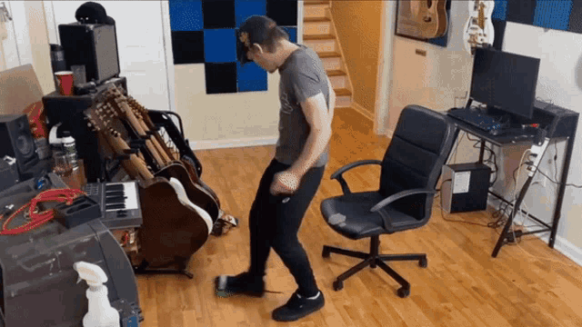 a man is dancing in a room with guitars and a desk