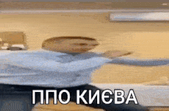 a man in a blue shirt is dancing in a room with a foreign language on his face .