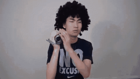 a young man with an afro is wearing a no excuses t-shirt and holding a bottle of soda .