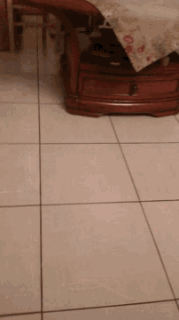a person 's hand is reaching out towards a mirror on a tiled floor
