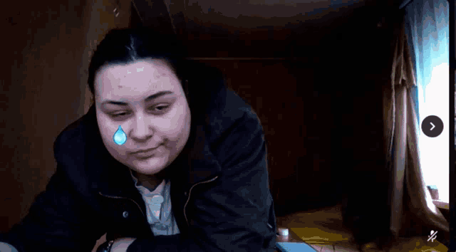 a woman with tears coming out of her eyes is sitting in front of a window