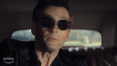 a man wearing sunglasses and a black shirt is sitting in a car with an amazon prime arrow in the background