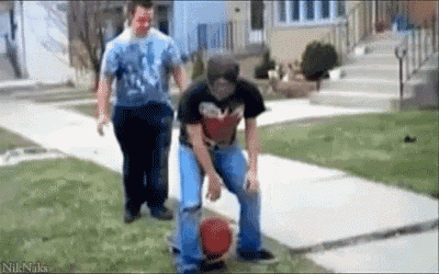 a man is kicking a basketball on the sidewalk while another man watches .