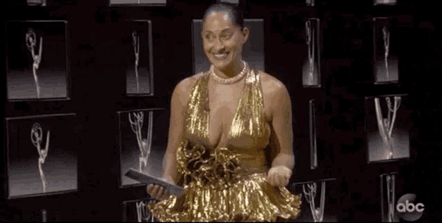a woman in a gold dress is holding a piece of paper and says `` good night '' .